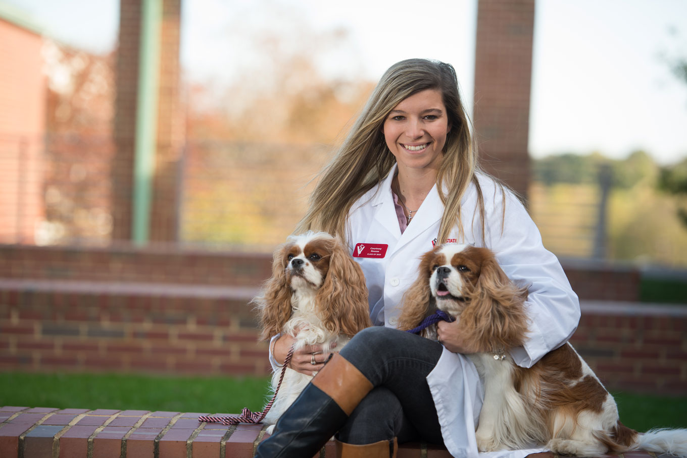 Veterinarian holding to dogs in lab coat.