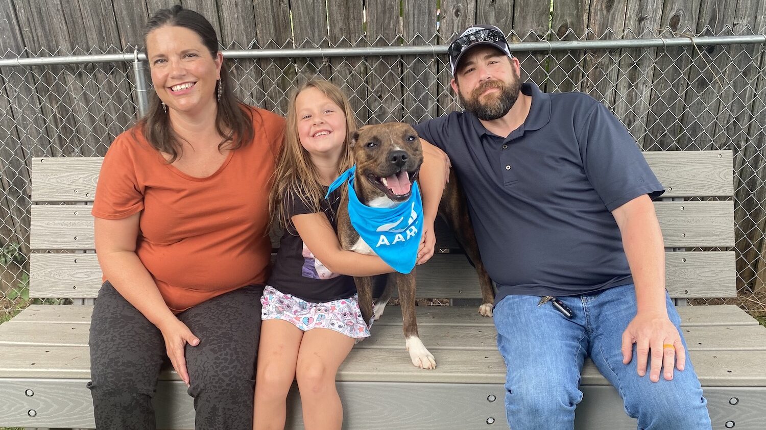 Family with an adopted dog sitting on a bench