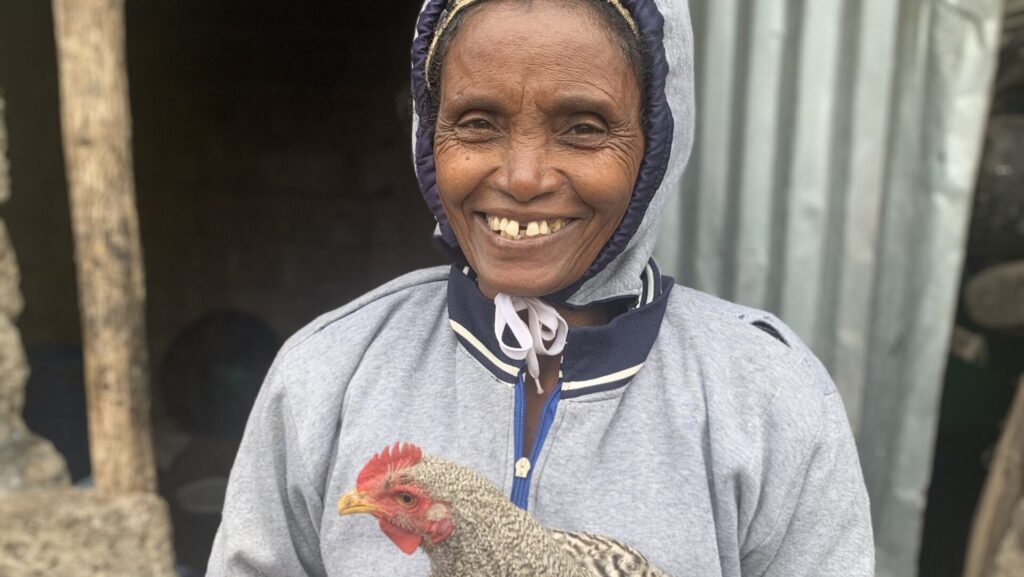 A woman in Ethiopia shows off a chicken.