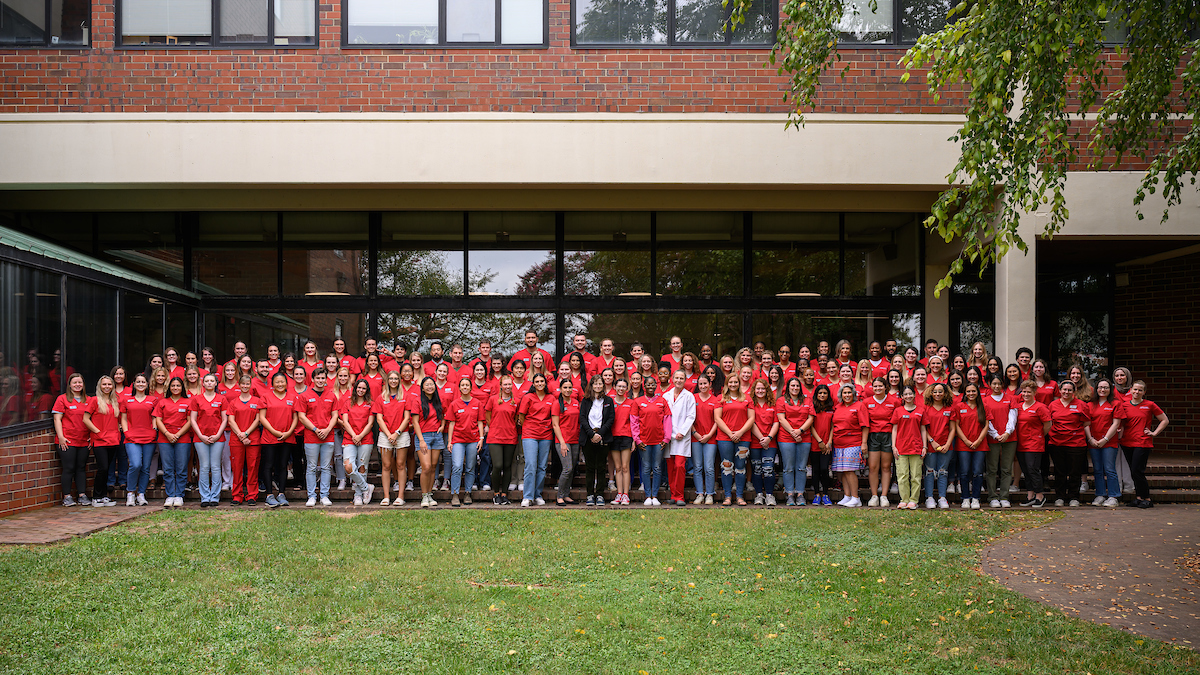 class of 2027 poses for a group picture in their new red scrub tops