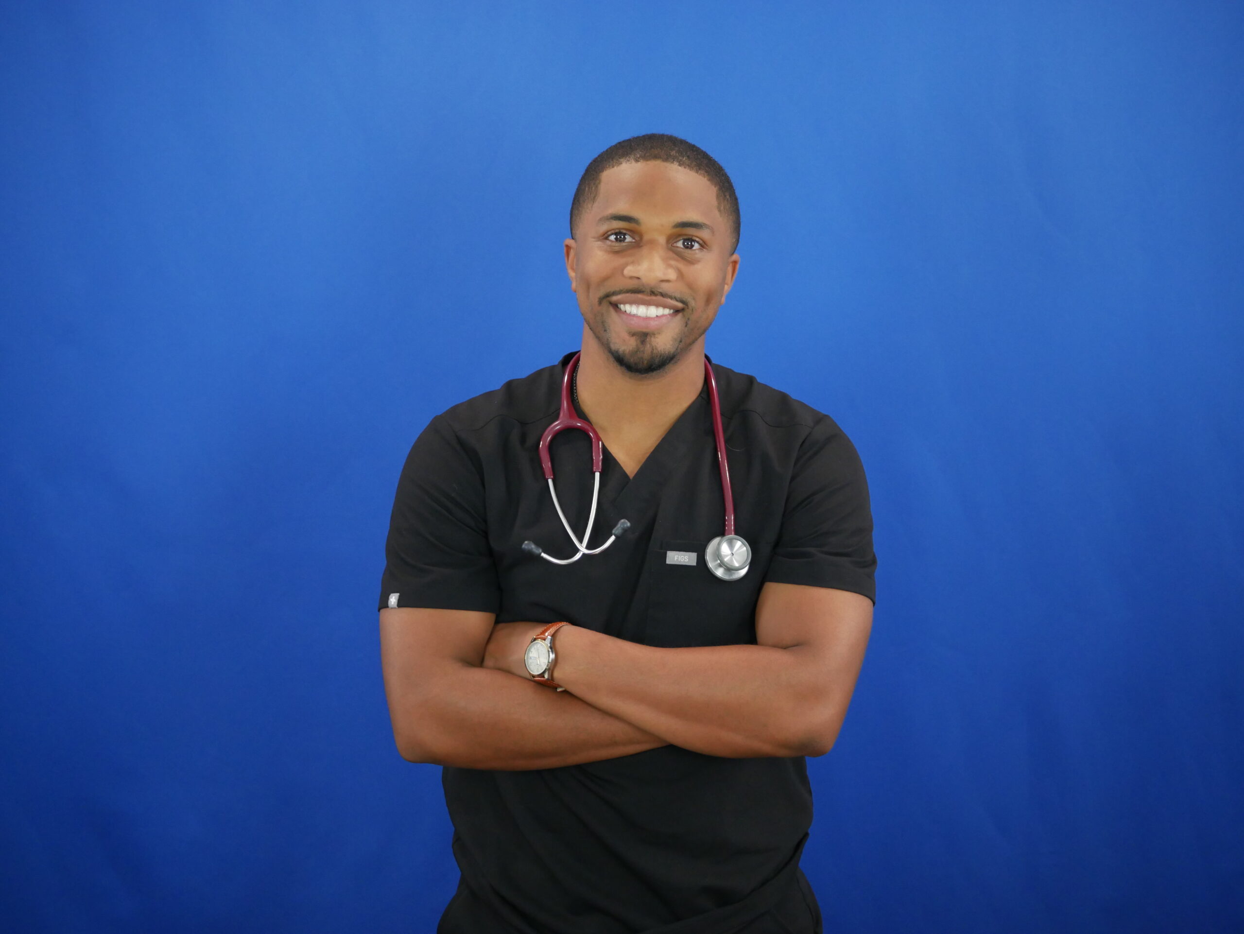 Small animal veterinarian Dr. Quincy Hawley stands with his arms crossed in front of a blue background.