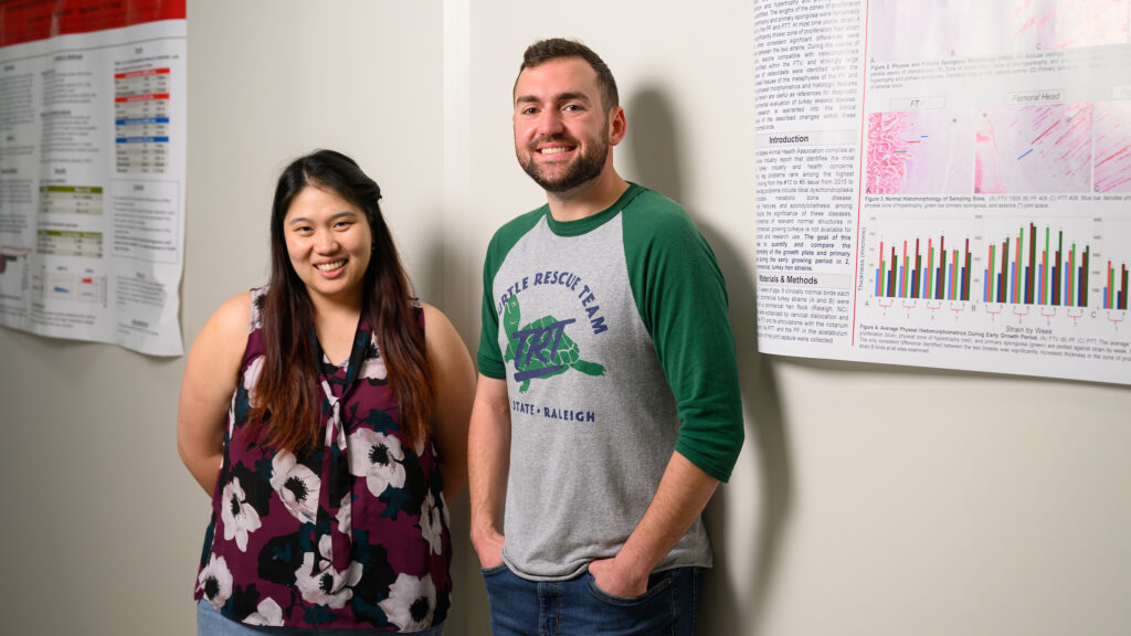 Assistant anatomic pathology professor Dr. Panchan Sitthicharoenchai stands next to her Veterinary Scholars Program mentee, Peyton Jameson, in front of posters in the pathology area of the NC State College of Veterinary Medicine.