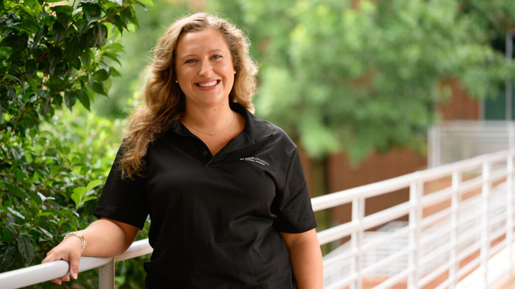 Lindsey Britton leans on a white railing outside the NC State College of Veterinary Medicine.