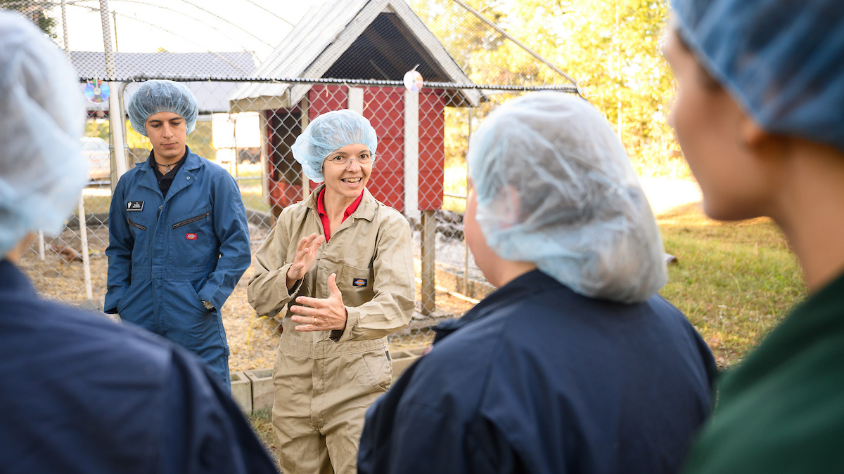 Dr. Rocio Crespo gestures as she teaches students during a visit to a chicken farm.