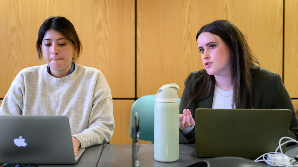 Donnell discusses a patient case while seated at a conference table. Another member of the veterinary care team sits beside her.