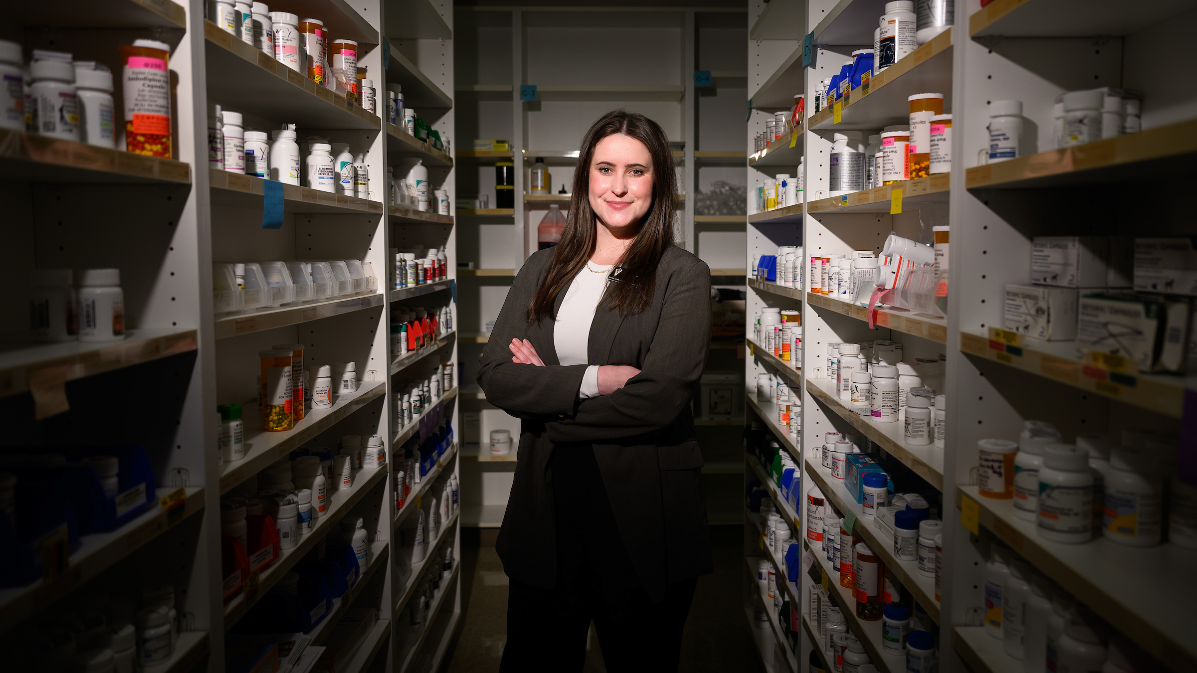 Veterinary pharmacist Dr. Cassie Donnell stands in between shelves of pill bottles at the NC State Veterinary Hospital's pharmacy.