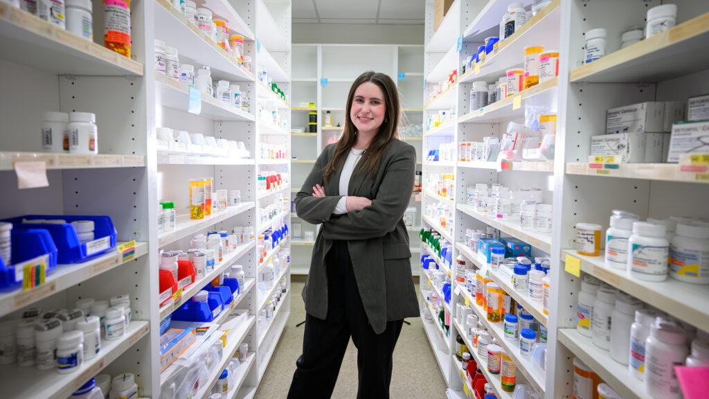 Donnell stands in between shelves of medications at the NC State Veterinary Hospital's pharmacy.