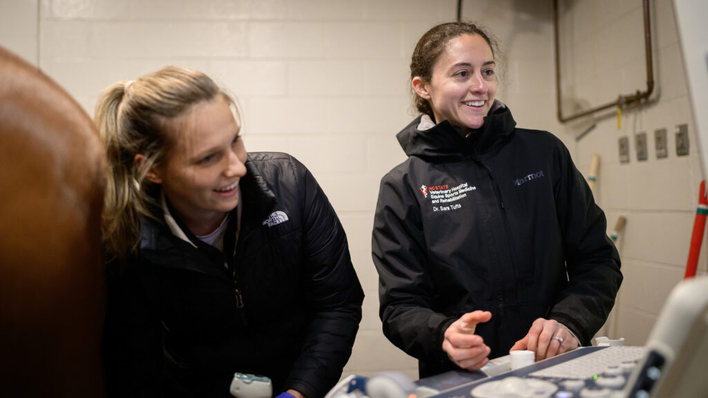 Tufts smiles while gesturing toward the ultrasound screen for another clinician to view.