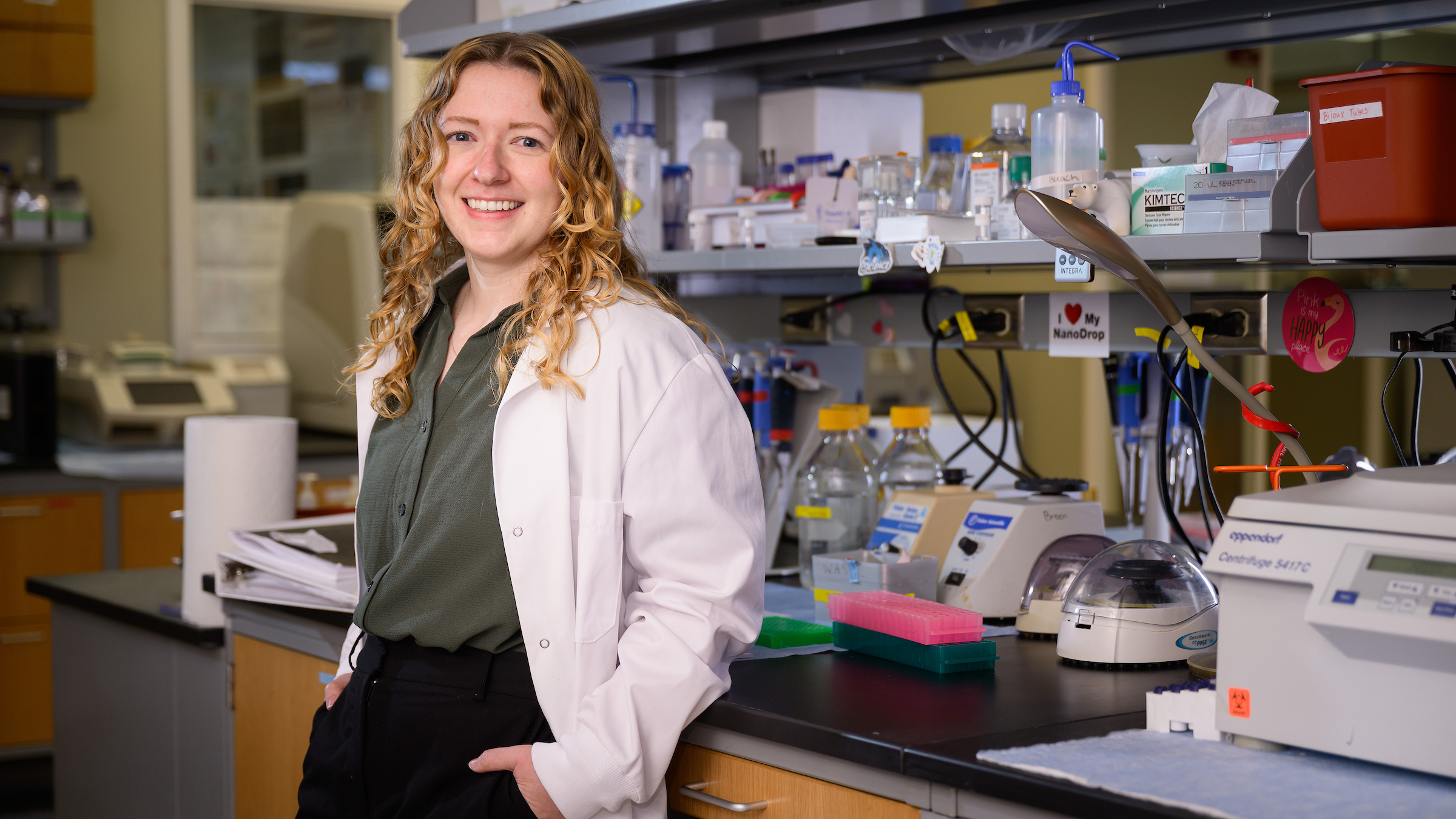 Dr. Megan Dillon leans against a lab bench, posing with her hands on her hips.