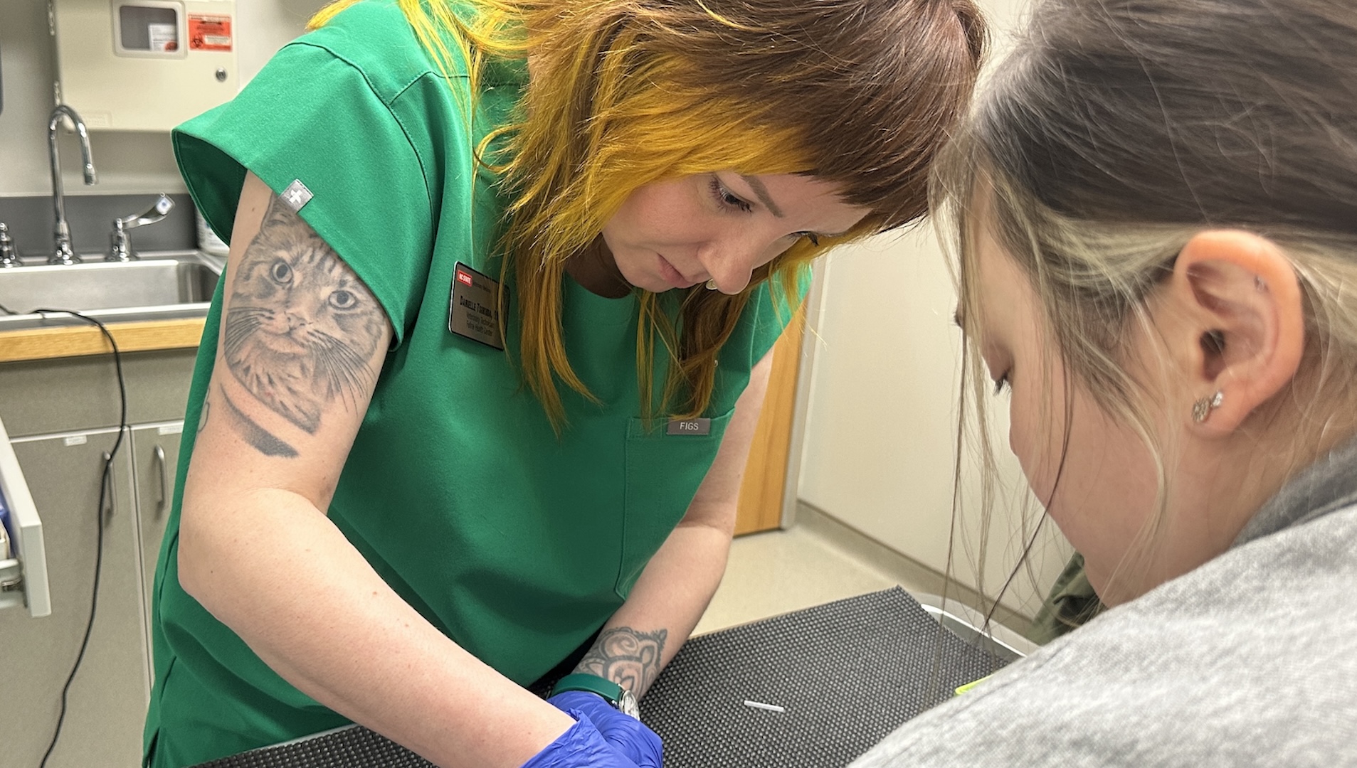 Danielle Tsukuba in green scrubs and a cat tattoo on her arm