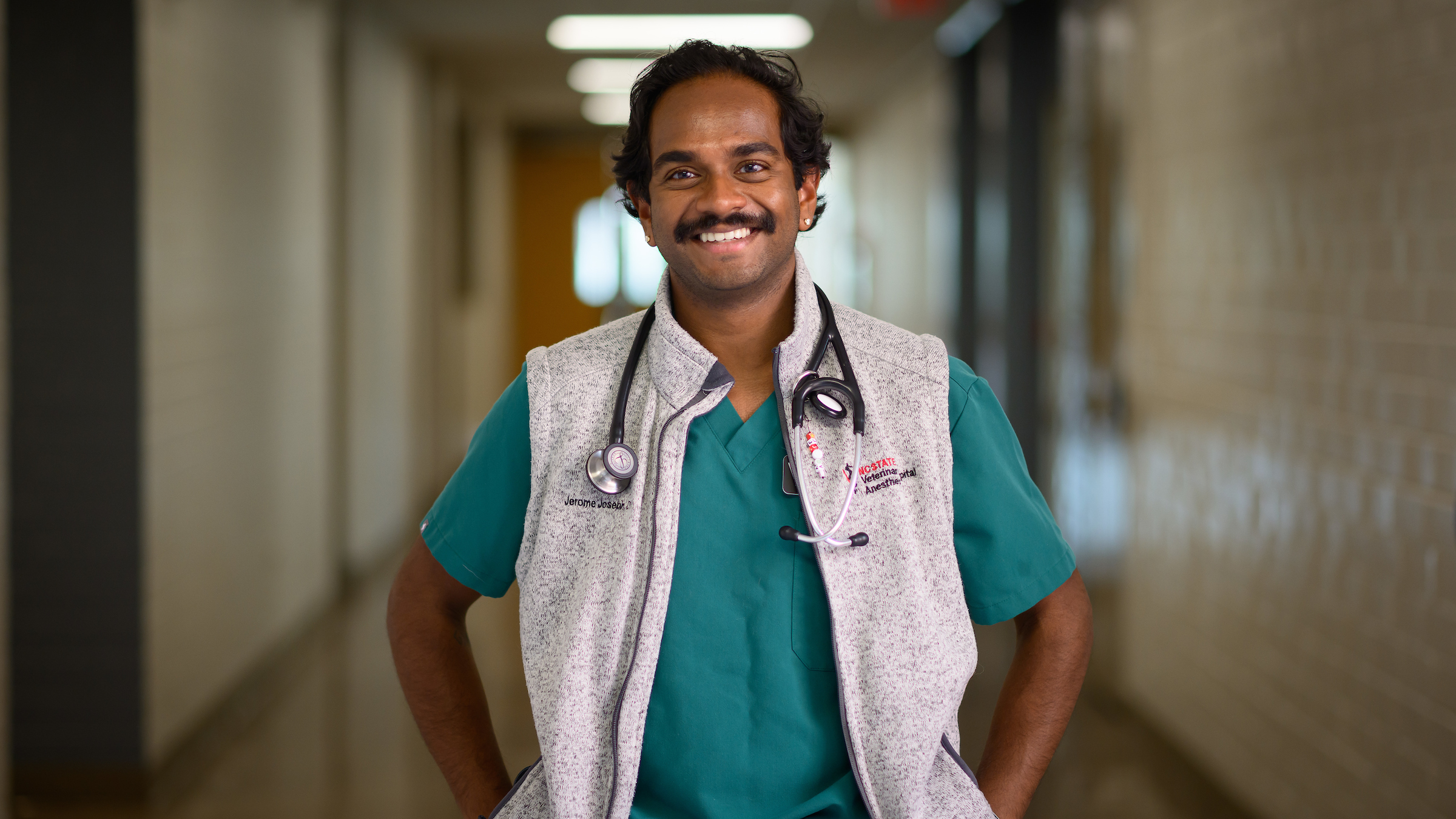 Dr. Jerome Joseph, an anesthesiology resident, smiles in a hallway at the NC State Veterinary Hospital.