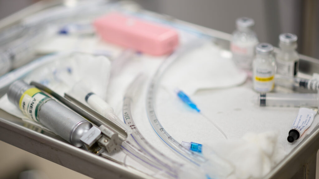 A table of anesthesia instruments, including tubes, needles and medication bottles.