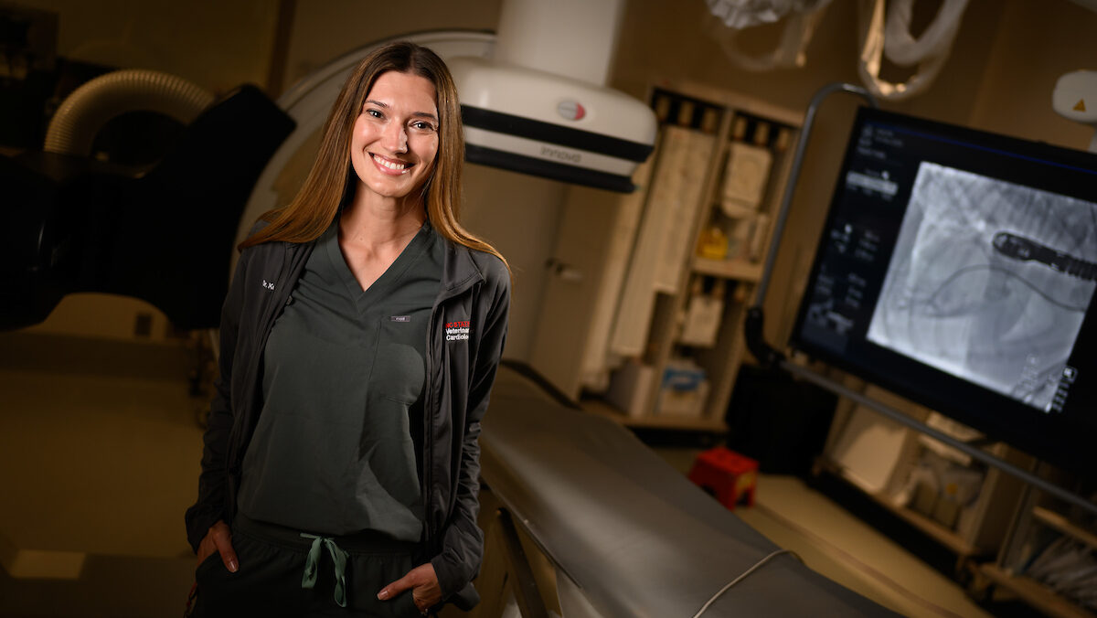 Dr. Kursten Pierce smiles at the camera while confidently standing in the cardiac cath lab at NC State's Veterinary Hospital.