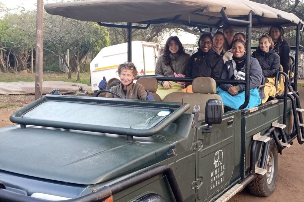 Aniya and a group of students smile from a safari vehicle