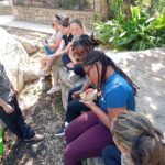 aniya gently holds a bearded dragon while a group of students watches