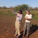 aniya and her instructor stand on a brownish0red dirt patch and use a special device